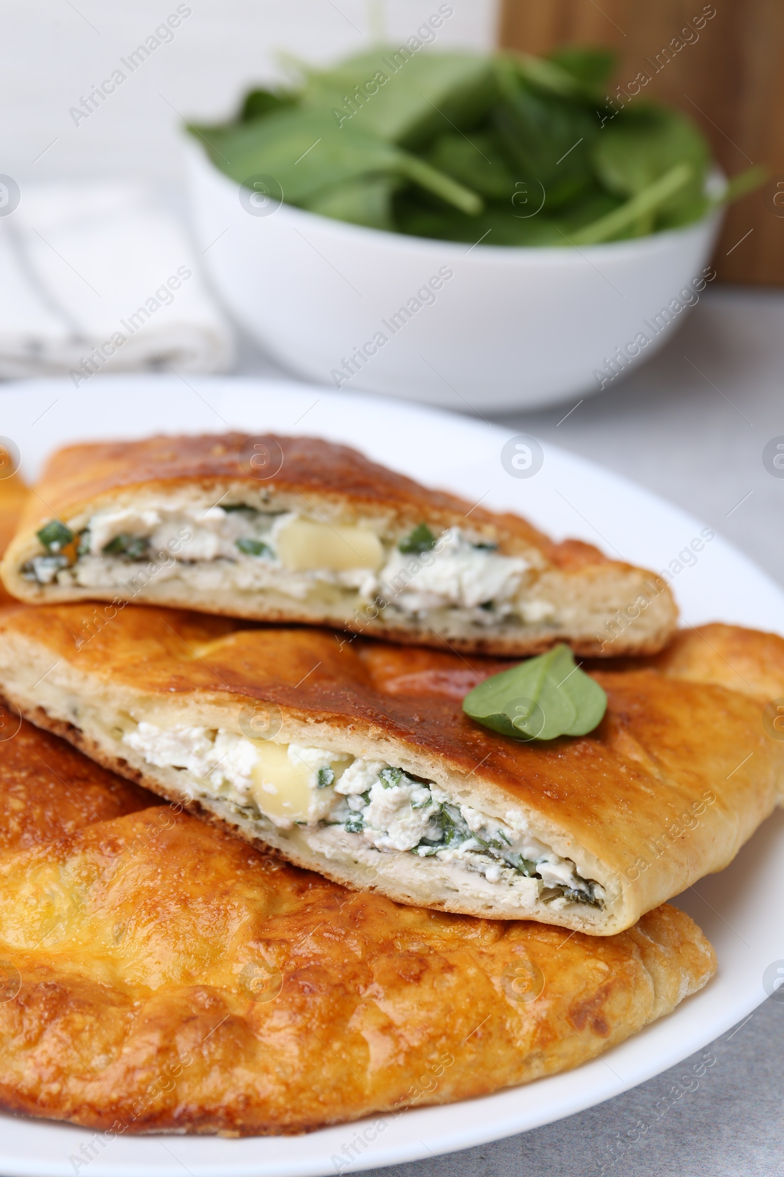 Photo of Tasty calzones with cheese and basil on table, closeup