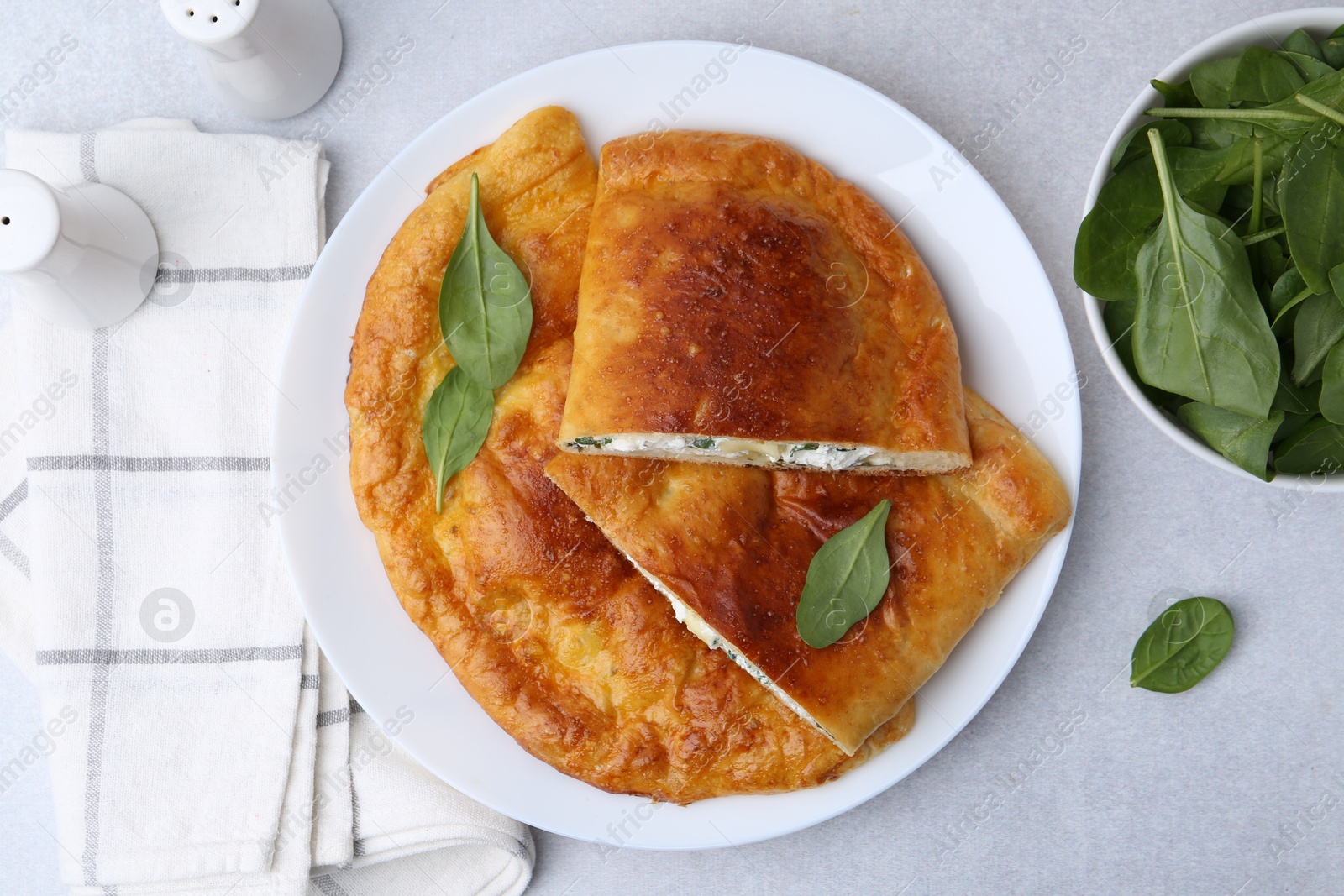 Photo of Tasty calzones with cheese and basil on light grey table, flat lay