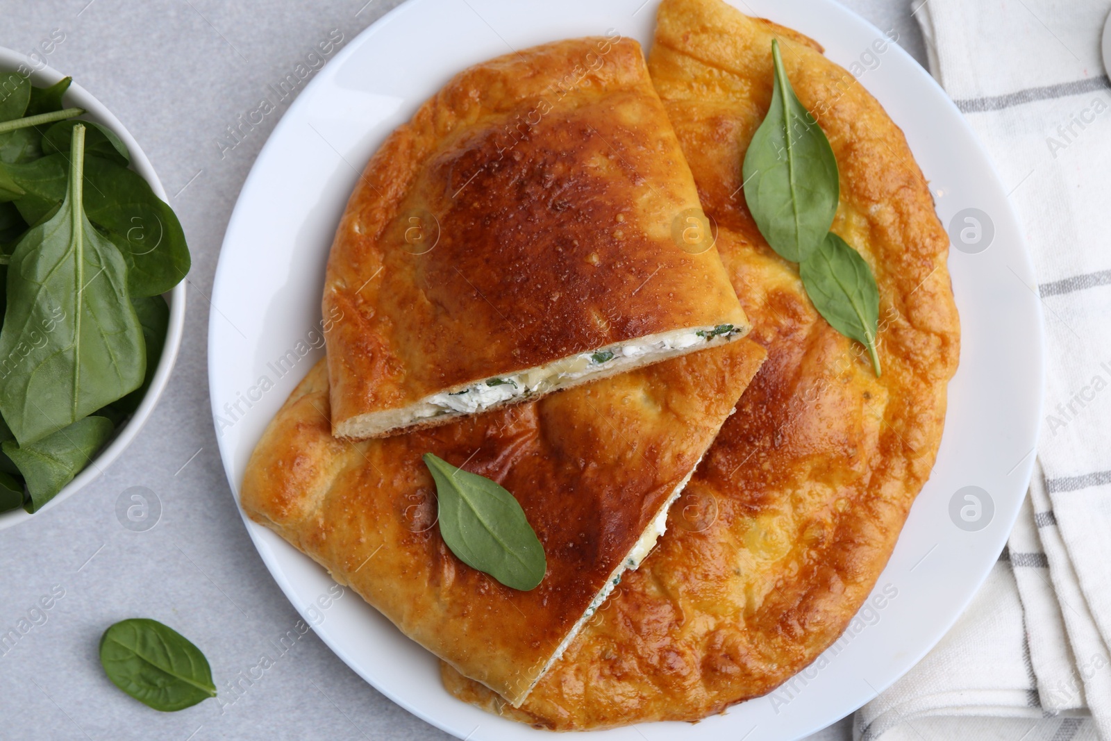 Photo of Tasty calzones with cheese and basil on light grey table, top view