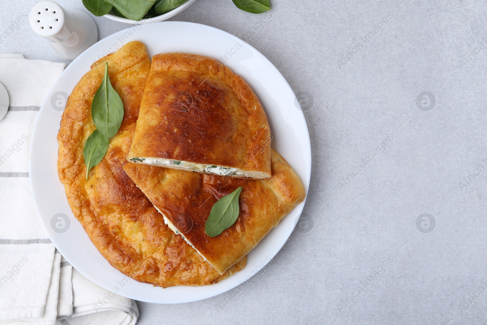 Photo of Tasty calzones with cheese and basil on light grey table, top view. Space for text