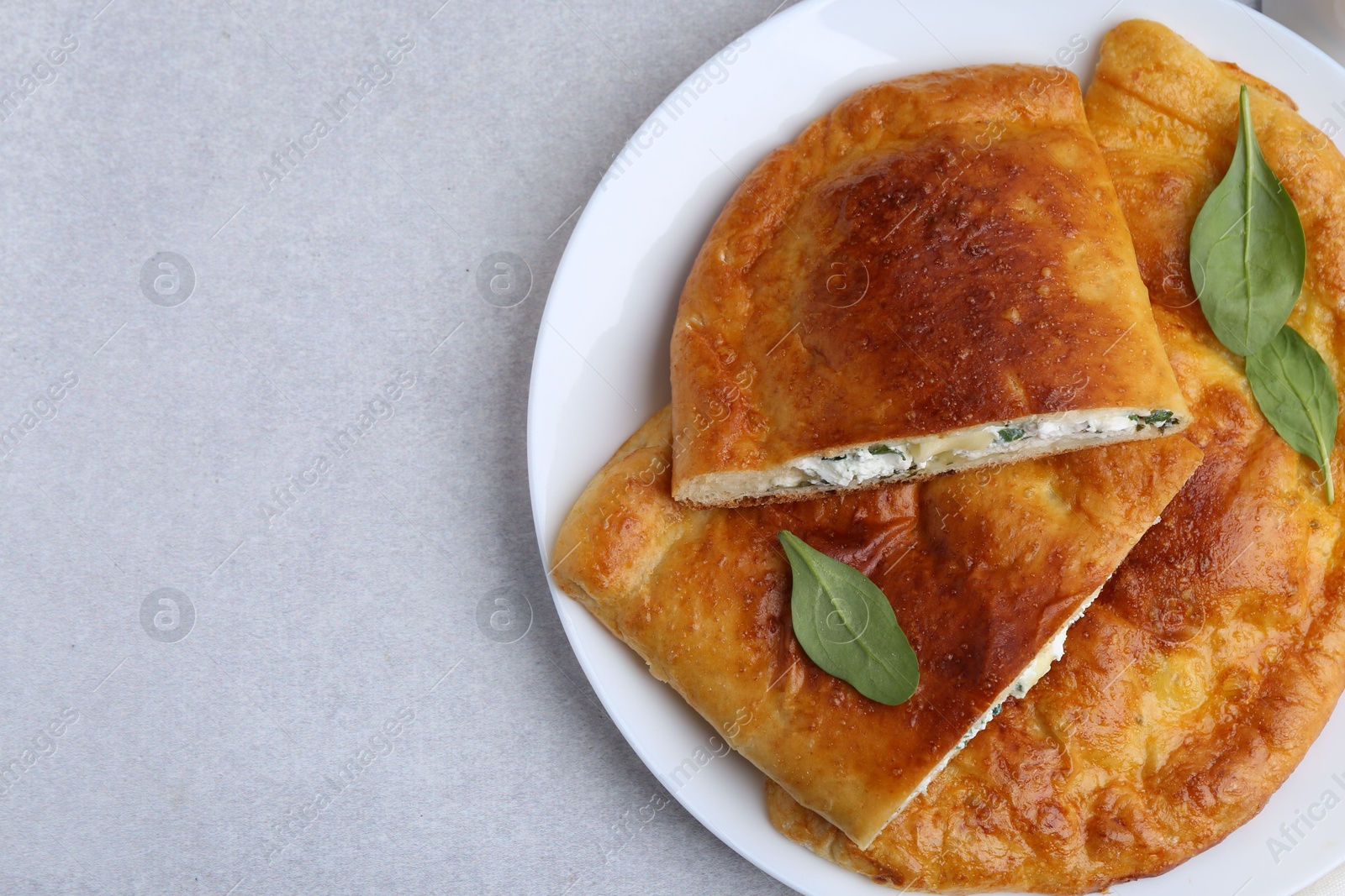 Photo of Tasty calzones with cheese and basil on light grey table, top view. Space for text