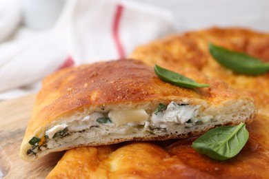 Photo of Pieces of tasty calzone with basil and cheese on table, closeup