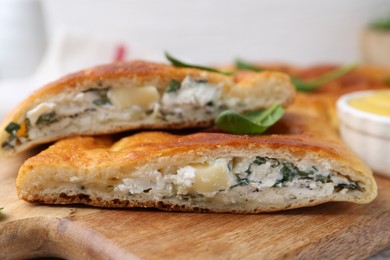 Photo of Pieces of tasty calzone with basil and cheese on table, closeup