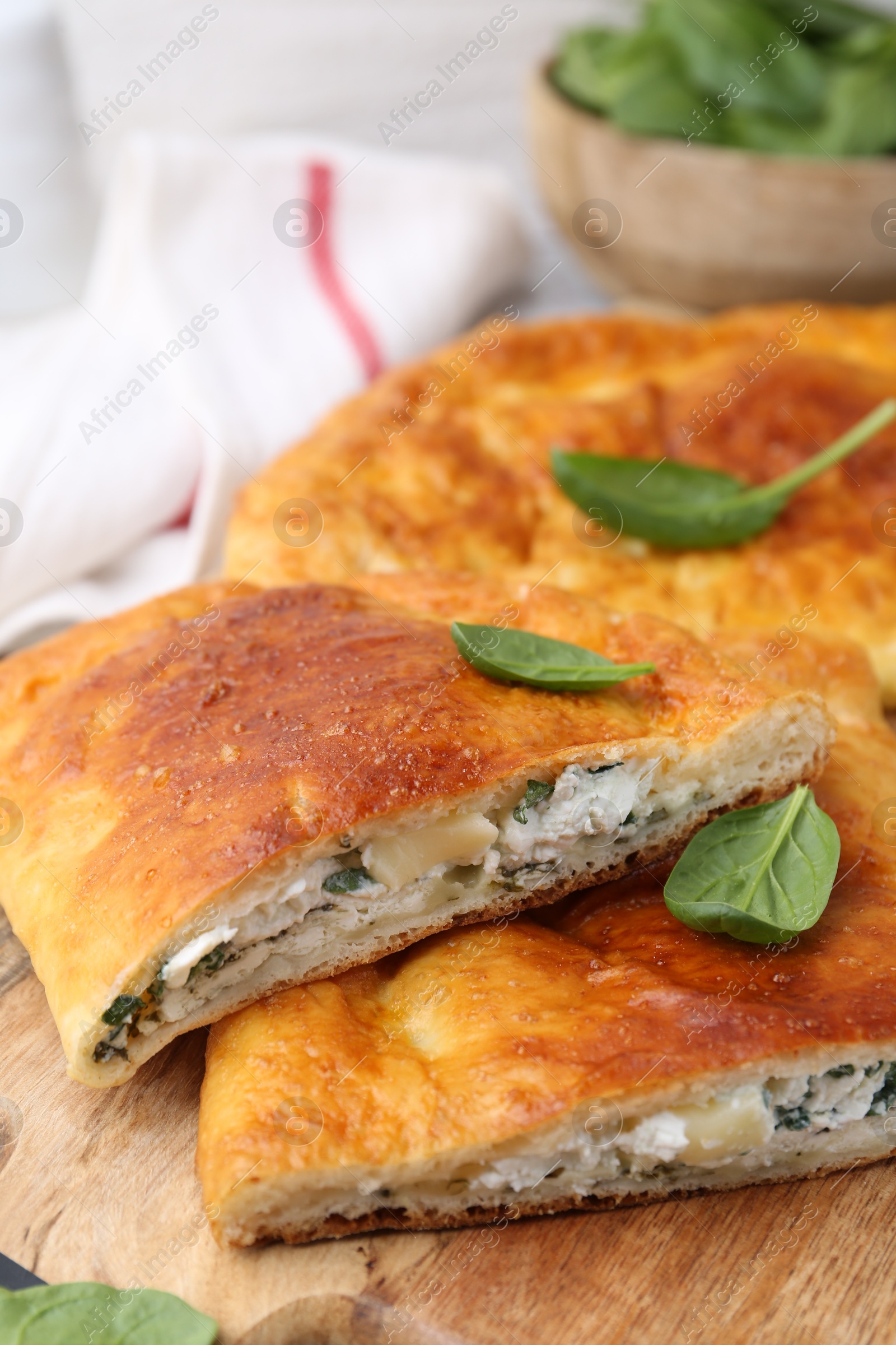 Photo of Pieces of tasty calzone with basil and cheese on table, closeup