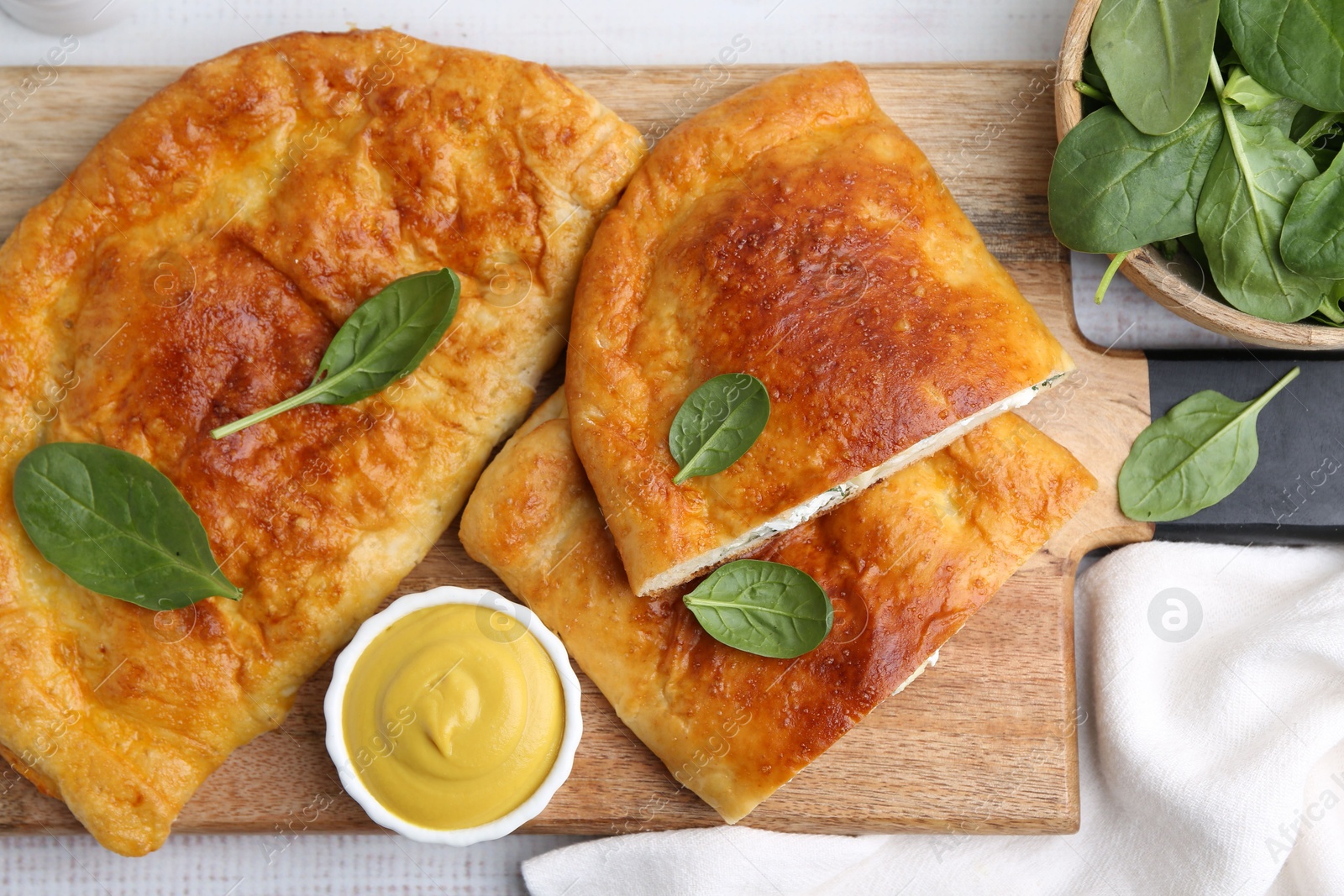 Photo of Tasty calzones with basil, cheese and sauce on table, top view