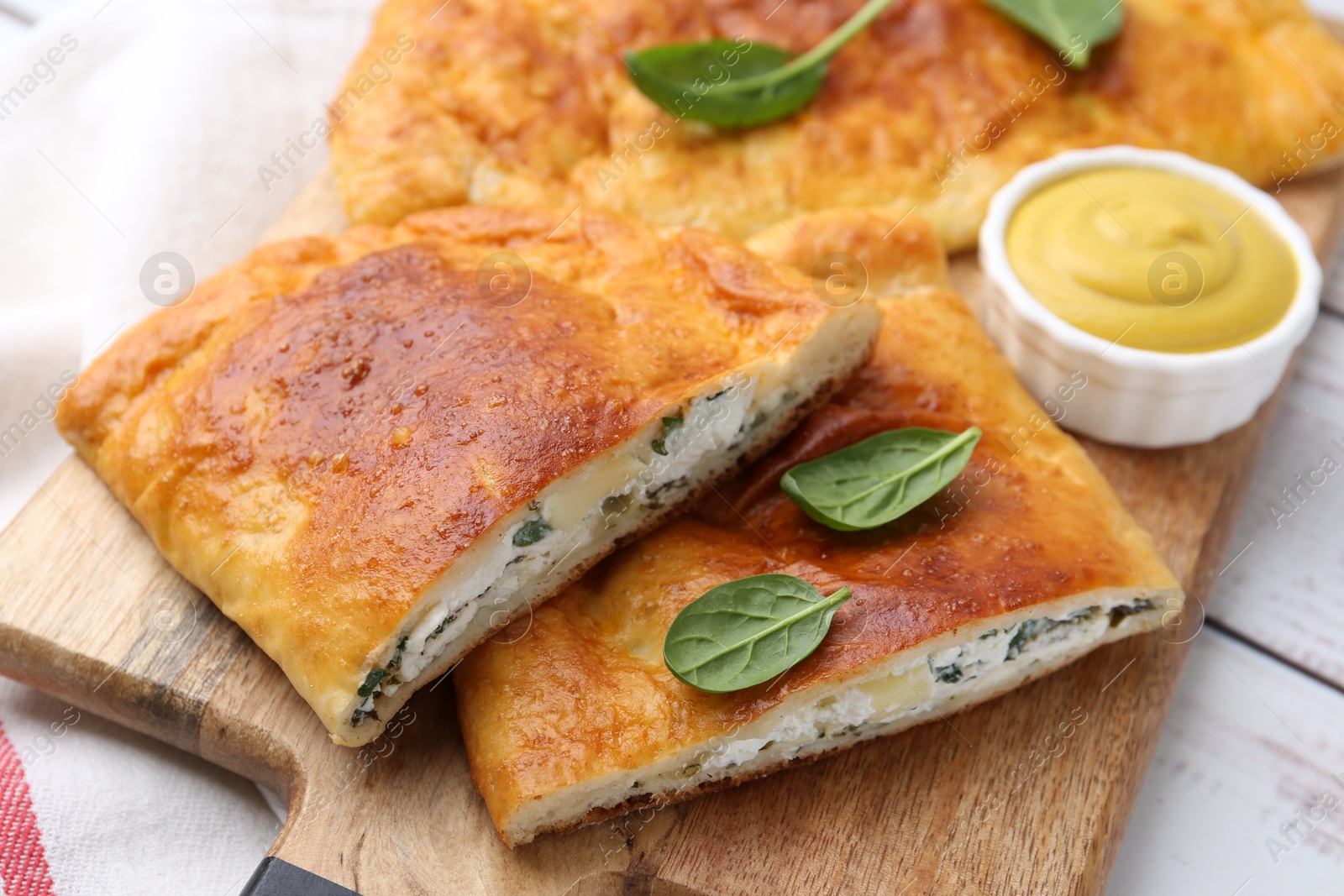 Photo of Tasty calzones with basil, cheese and sauce on table, closeup