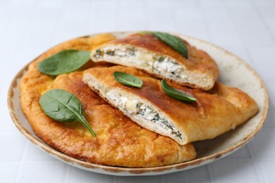 Photo of Tasty calzones with basil and cheese on white table, closeup