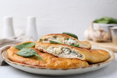 Photo of Tasty calzones with basil and cheese on white table, closeup