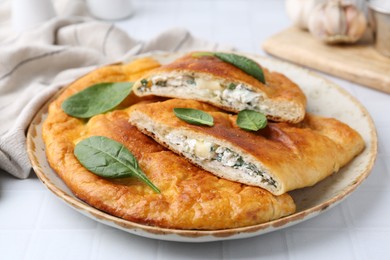 Photo of Tasty calzones with basil and cheese on white table, closeup