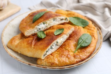 Photo of Tasty calzones with basil and cheese on white table, closeup