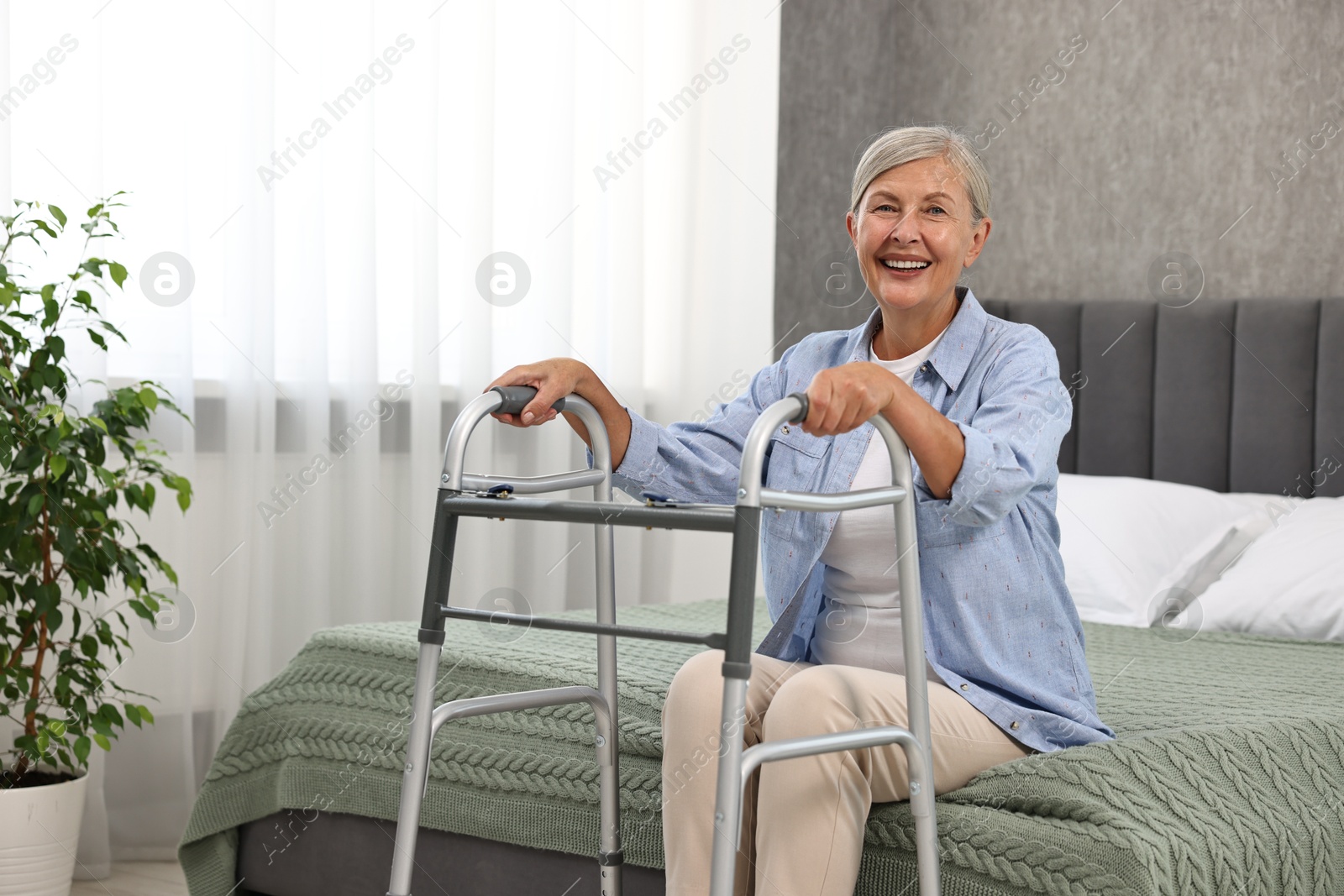 Photo of Senior woman with walking frame on bed at home