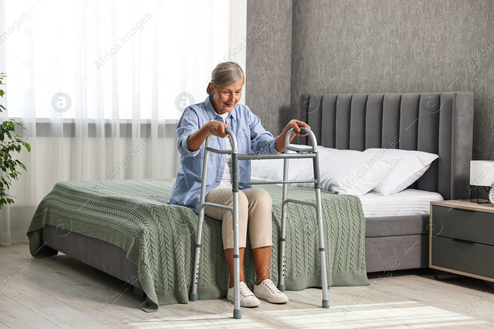 Photo of Senior woman with walking frame on bed at home