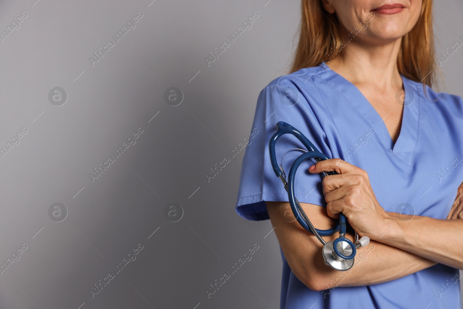 Photo of Doctor with stethoscope on gray background, closeup. Space for text