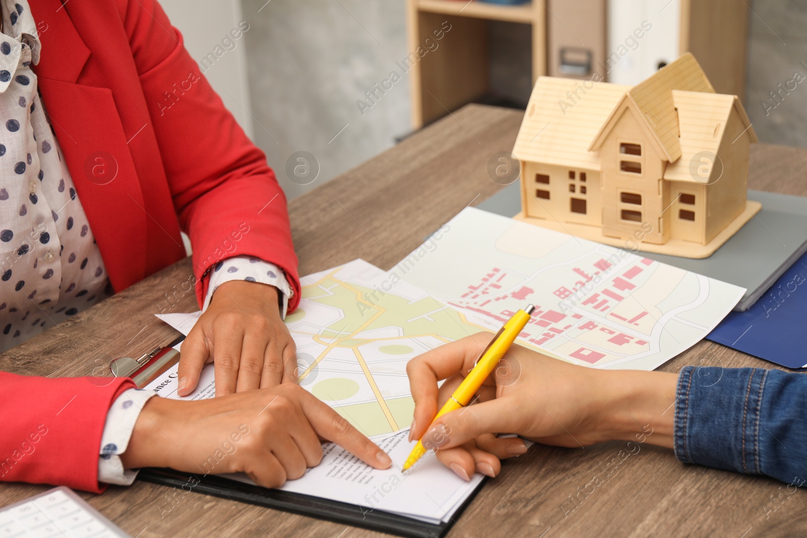 Photo of Real estate agent working with client at wooden table, closeup