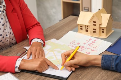 Real estate agent working with client at wooden table, closeup