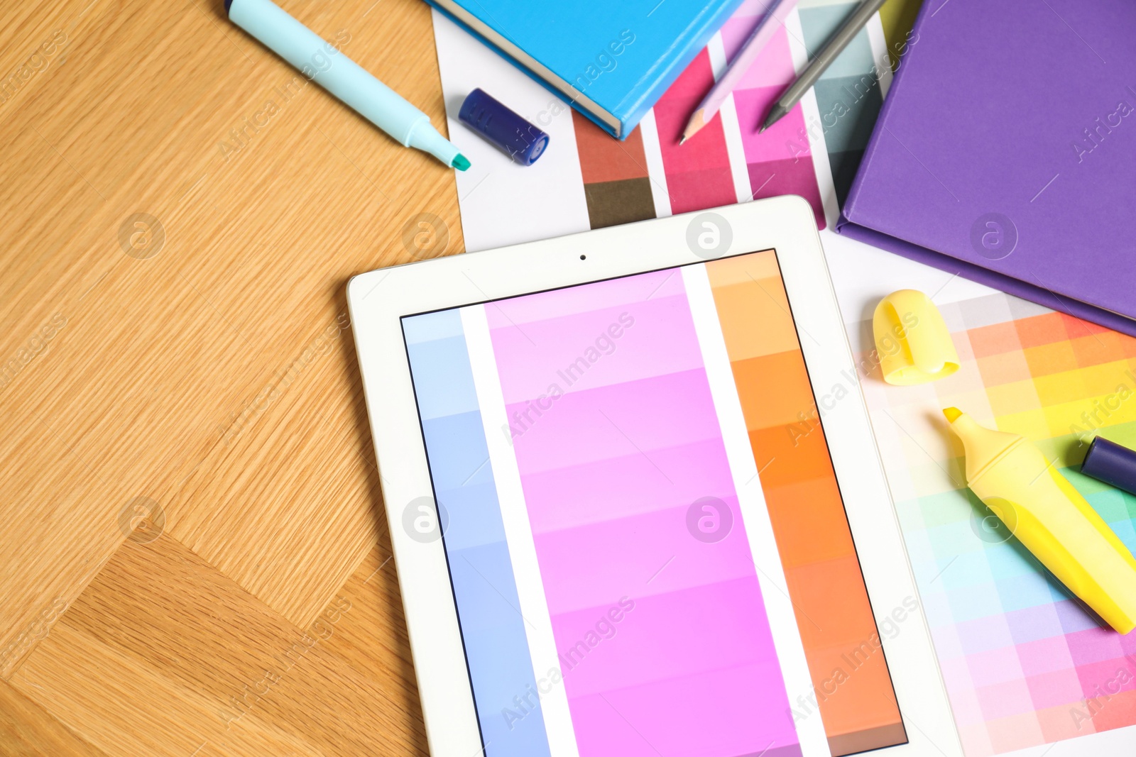 Photo of Designer's workplace with tablet, palettes and stationery on wooden table, top view