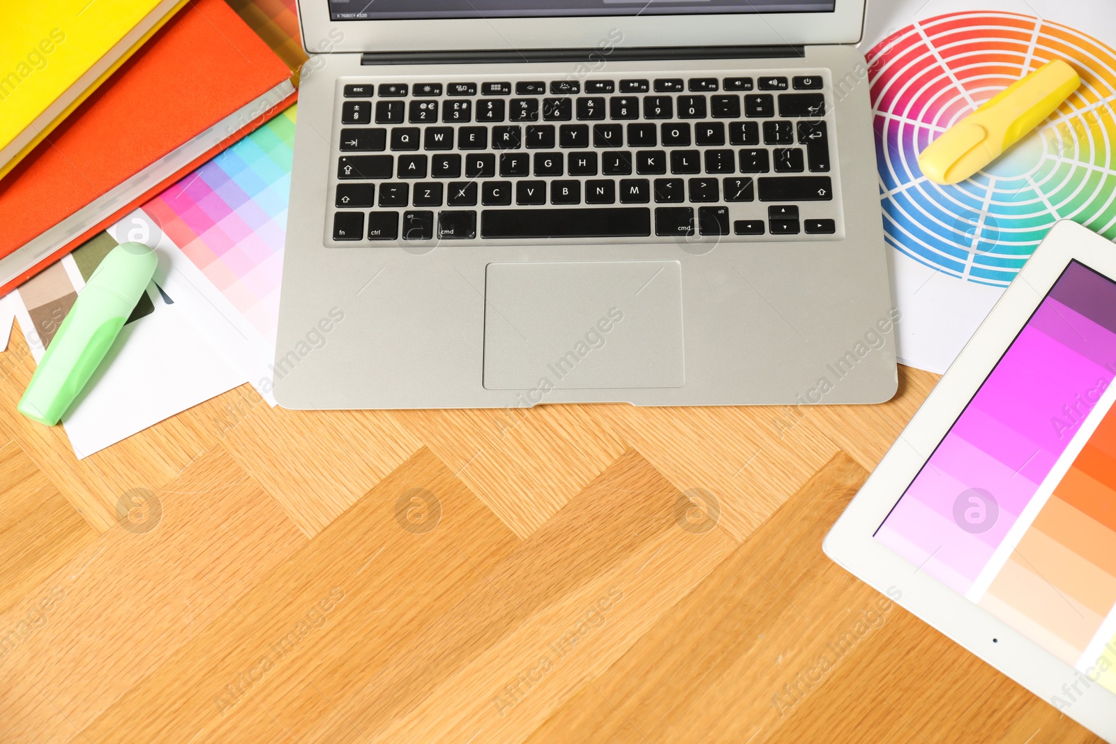 Photo of Designer's workplace with laptop, tablet, palettes and stationery on wooden table