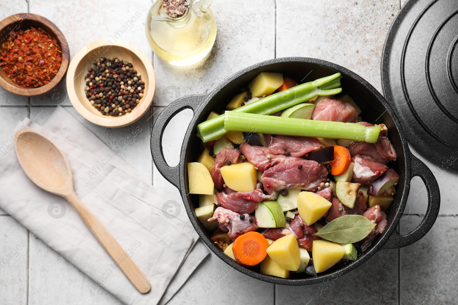 Photo of Cooking stew. Uncooked meat and vegetables in pot on white tiled table, flat lay