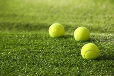 Photo of Tennis balls on green artificial grass, space for text