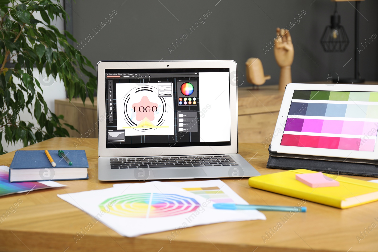 Photo of Designer's workplace with laptop, tablet, stationery and palettes on wooden table indoors