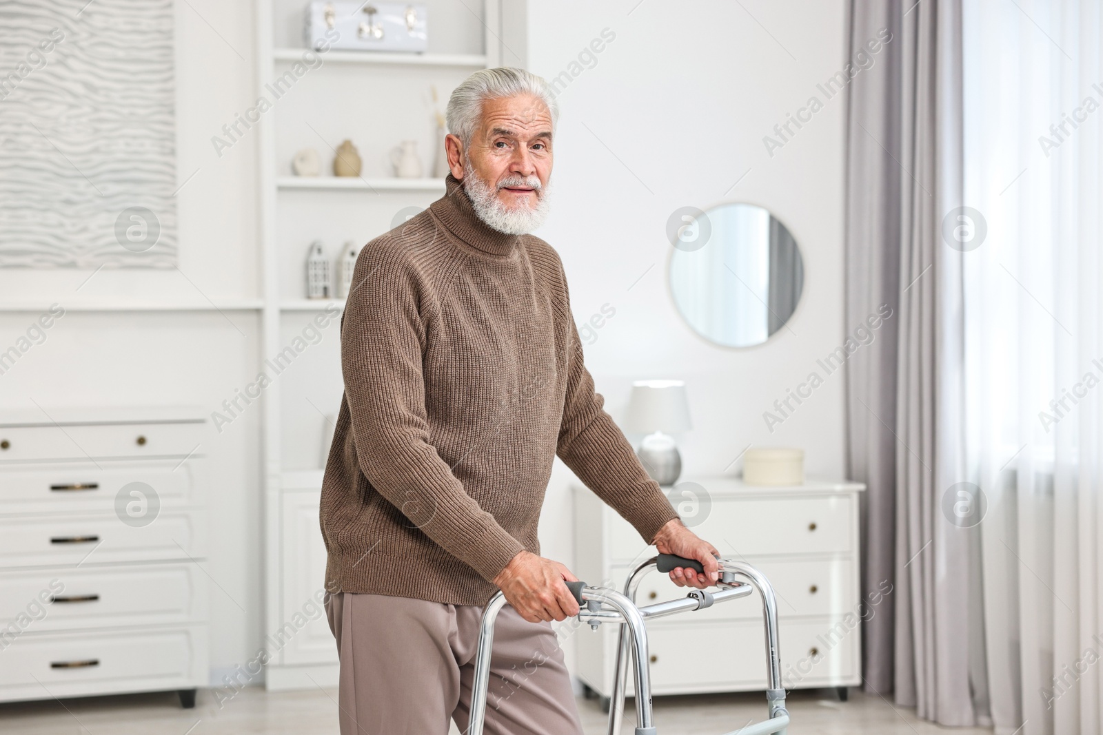 Photo of Senior man using walking frame at home