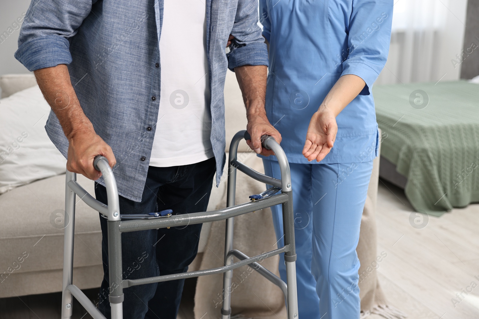 Photo of Nurse helping senior man with walking frame indoors, closeup