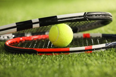 Tennis rackets and ball on green artificial grass, closeup