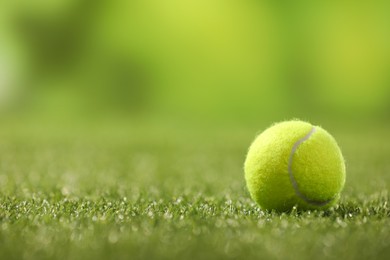 Photo of Tennis ball on green artificial grass, space for text