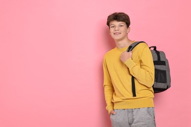 Photo of Happy teenage boy with backpack on pink background, space for text