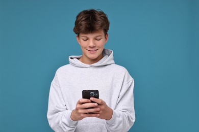 Photo of Teenage boy with smartphone on light blue background