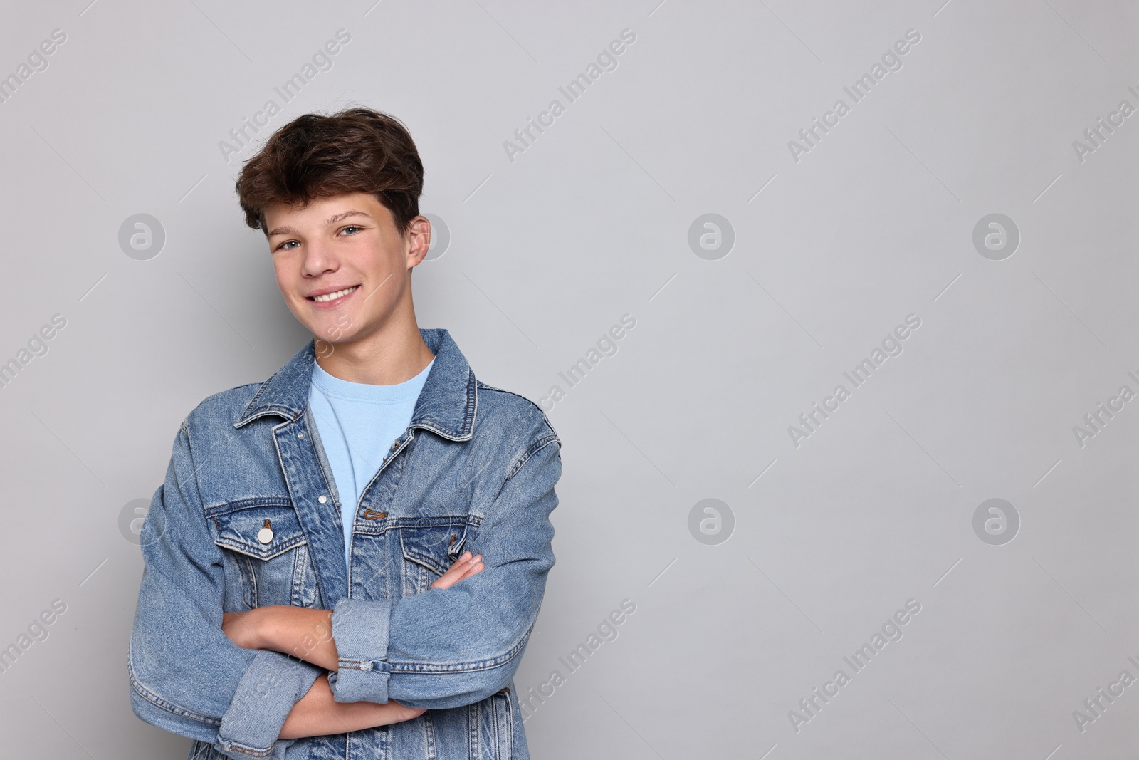 Photo of Portrait of happy teenage boy on light grey background, space for text