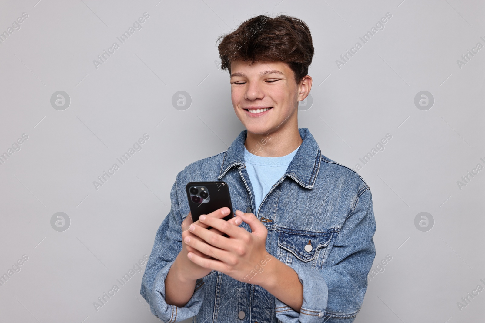 Photo of Teenage boy with smartphone on light grey background