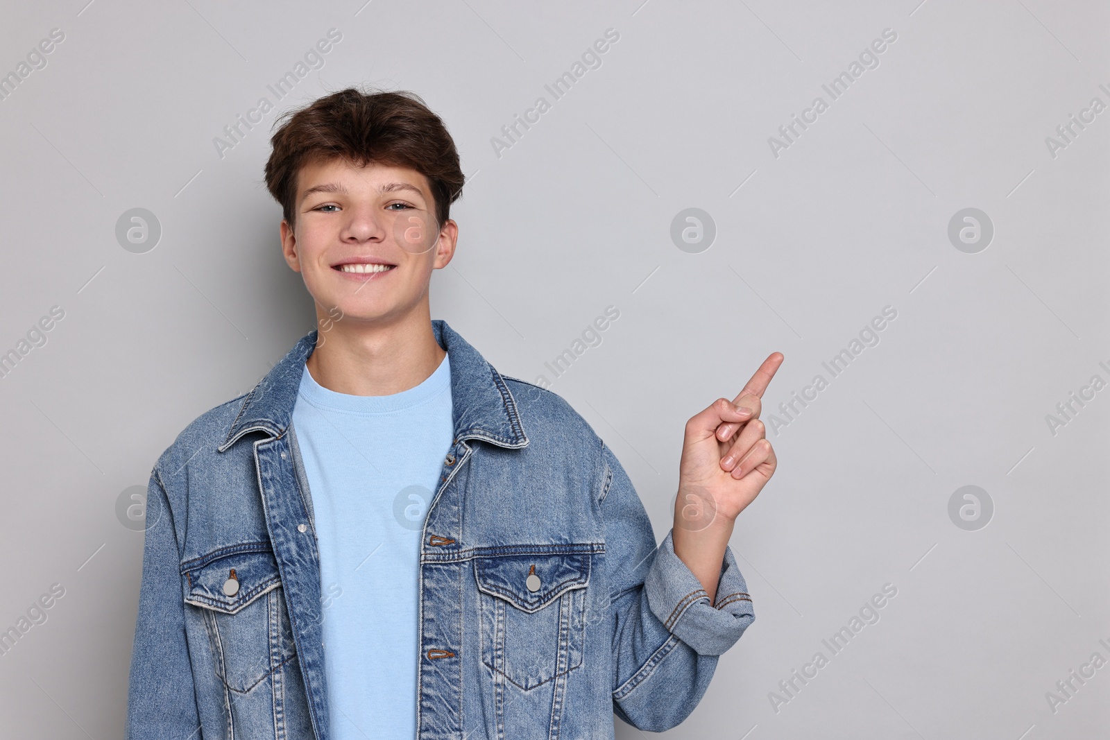 Photo of Happy teenage boy on light grey background, space for text