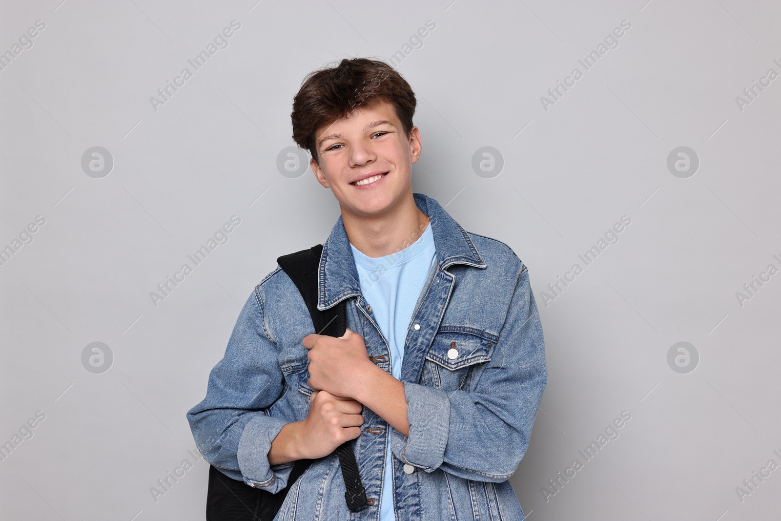 Photo of Happy teenage boy with backpack on light grey background