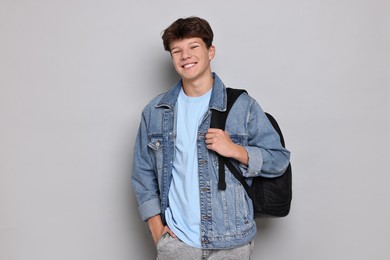 Photo of Happy teenage boy with backpack on light grey background