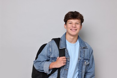 Photo of Happy teenage boy with backpack on light grey background