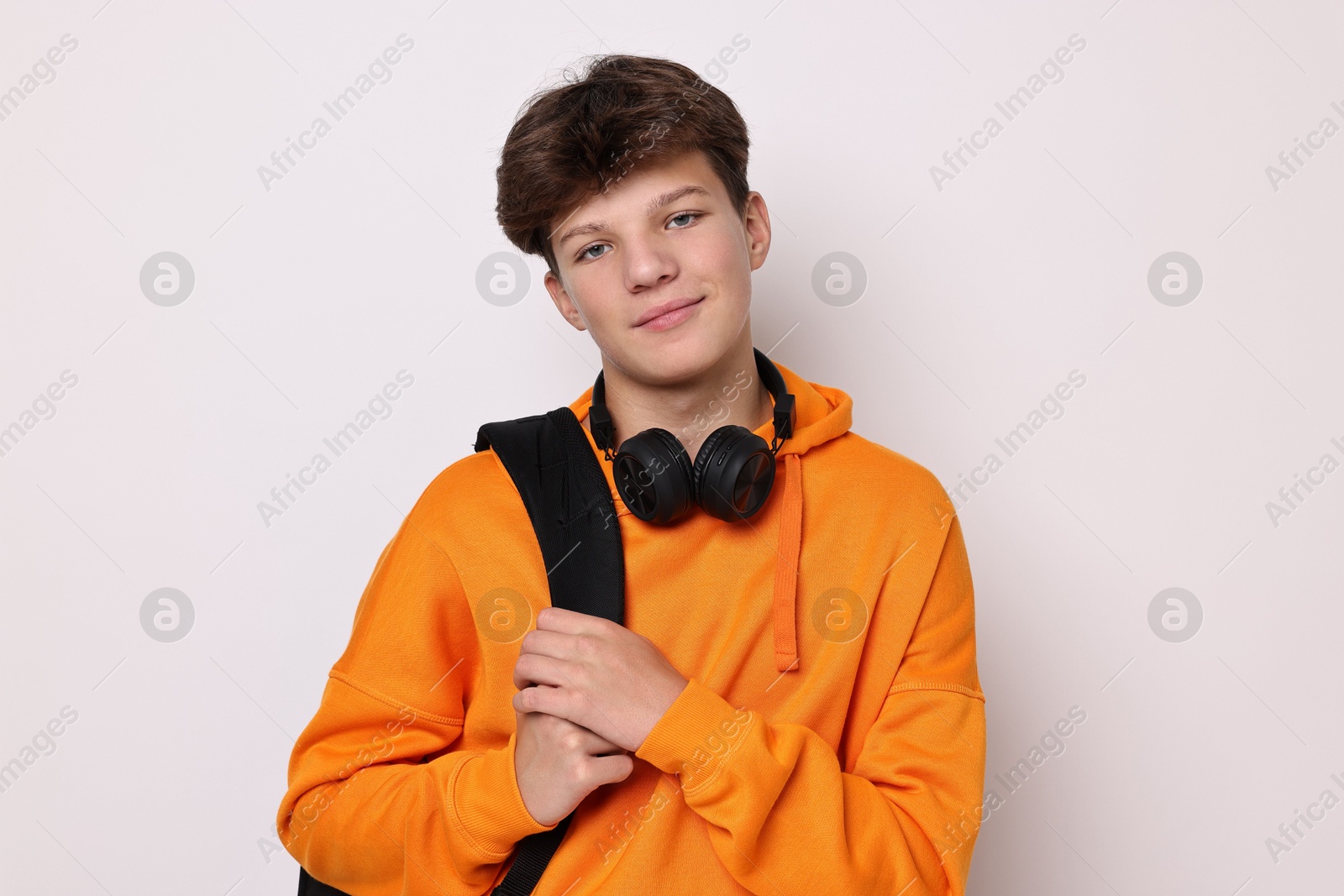 Photo of Teenage boy with headphones and backpack on white background