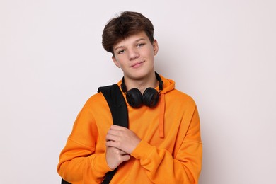 Photo of Teenage boy with headphones and backpack on white background