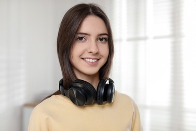 Photo of Portrait of happy teenage girl with headphones at home