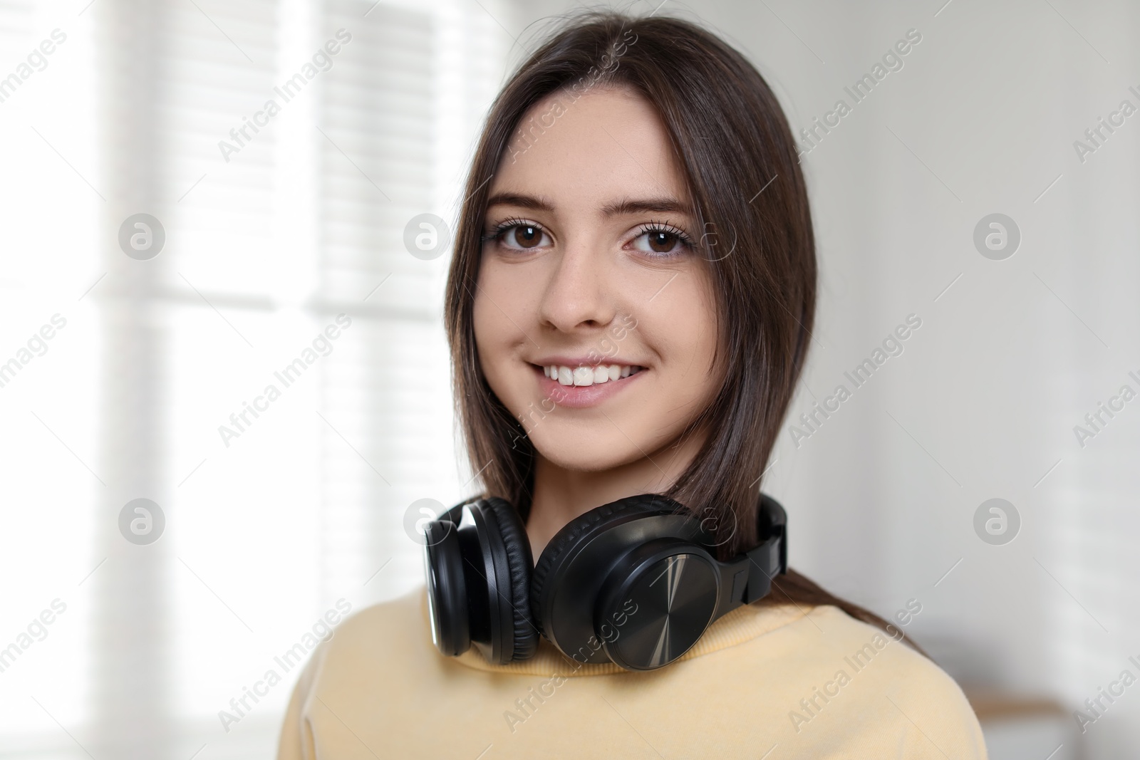 Photo of Portrait of happy teenage girl with headphones at home