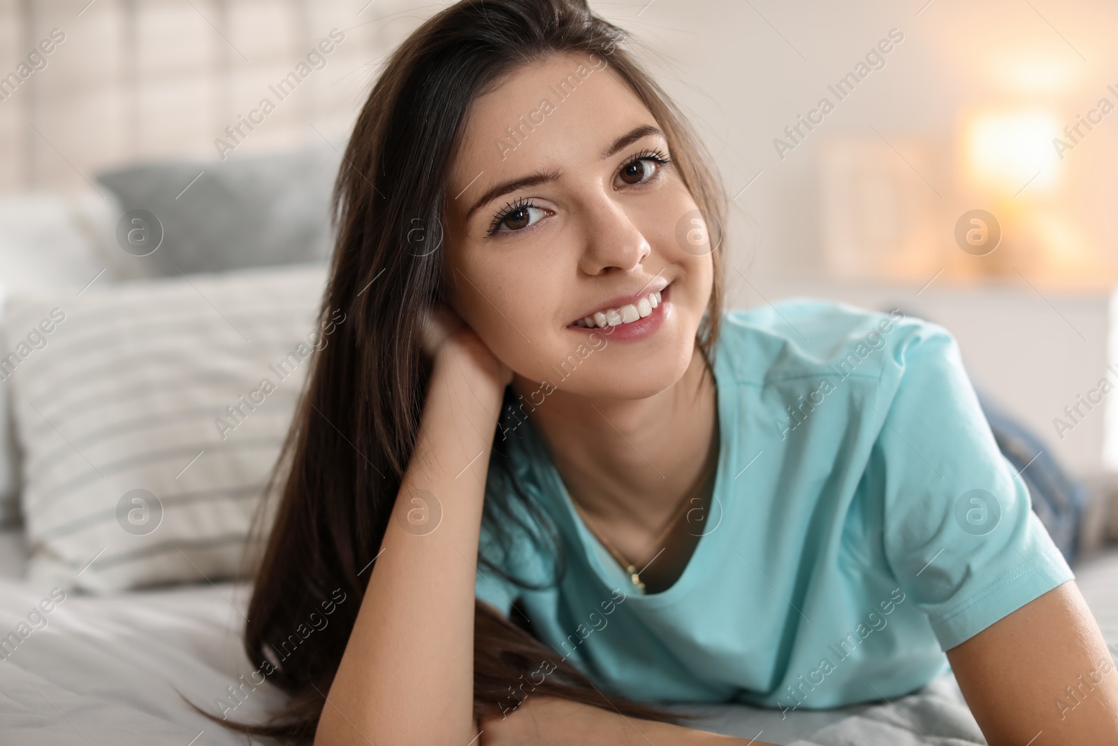 Photo of Portrait of smiling teenage girl on bed at home