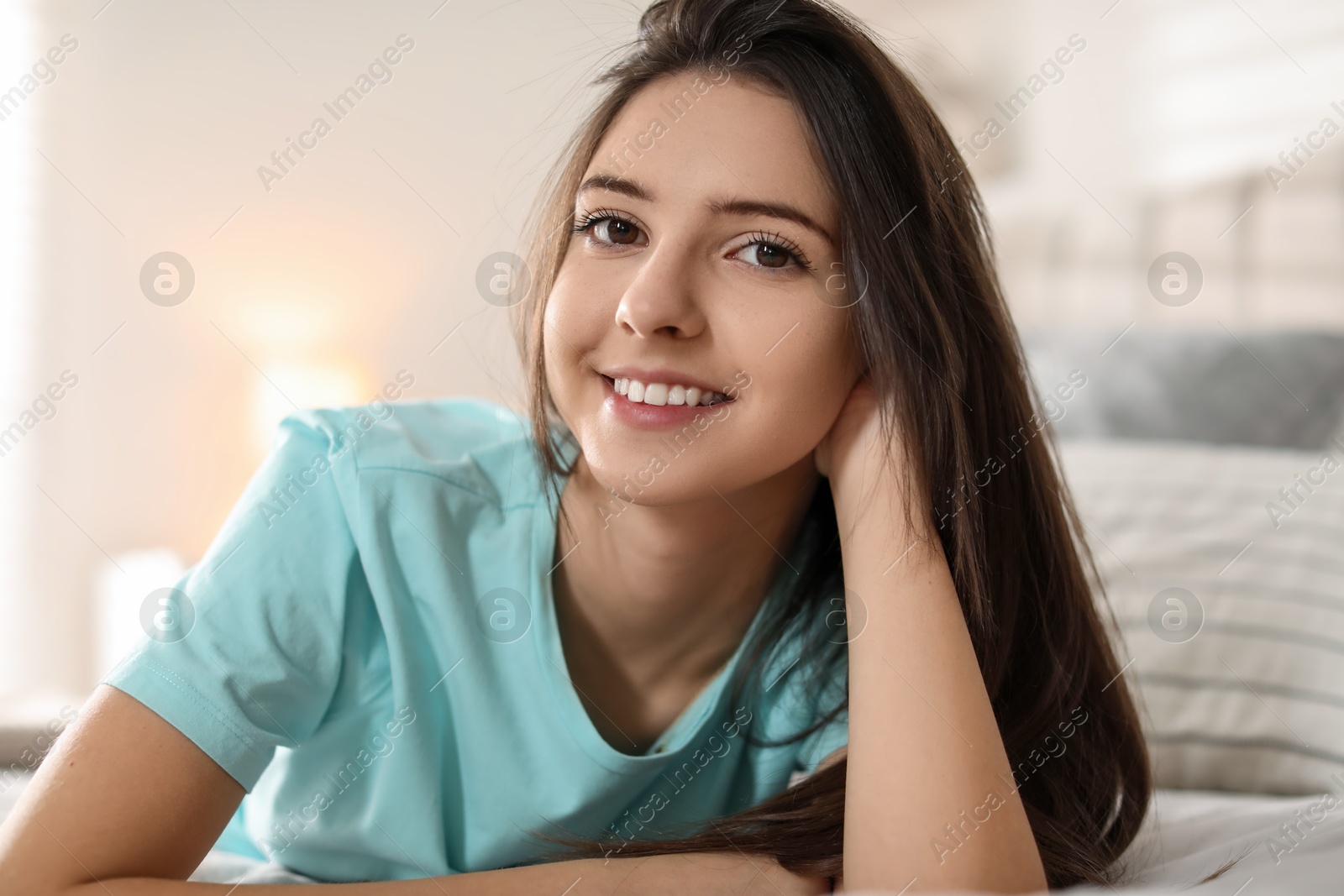 Photo of Portrait of smiling teenage girl on bed at home