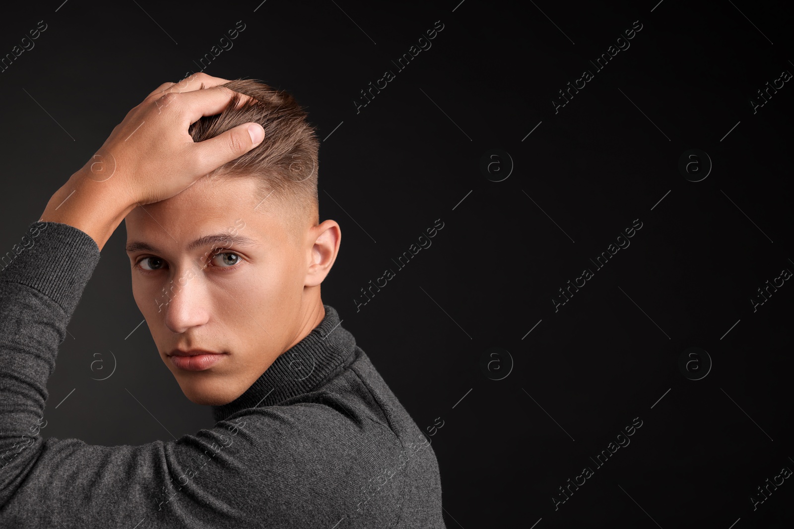 Photo of Confident young man with stylish haircut on black background. Space for text