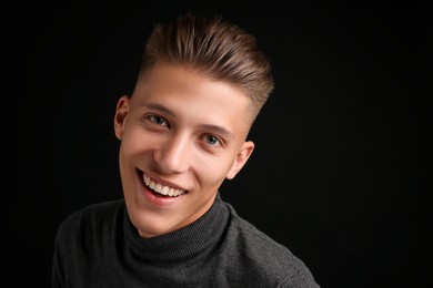 Photo of Confident young man with stylish haircut on black background