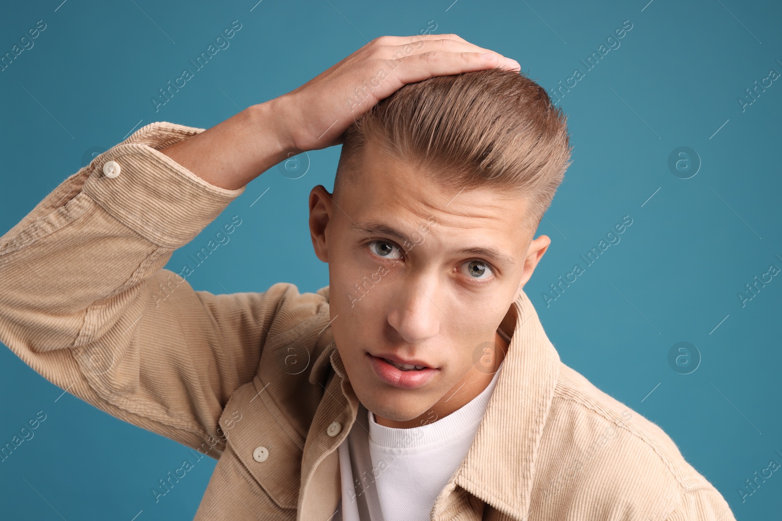 Photo of Confident young man with stylish haircut on blue background