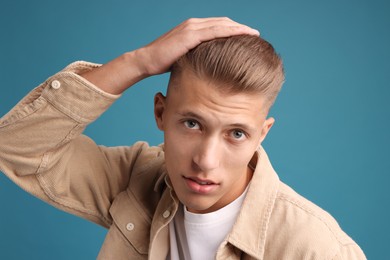 Photo of Confident young man with stylish haircut on blue background