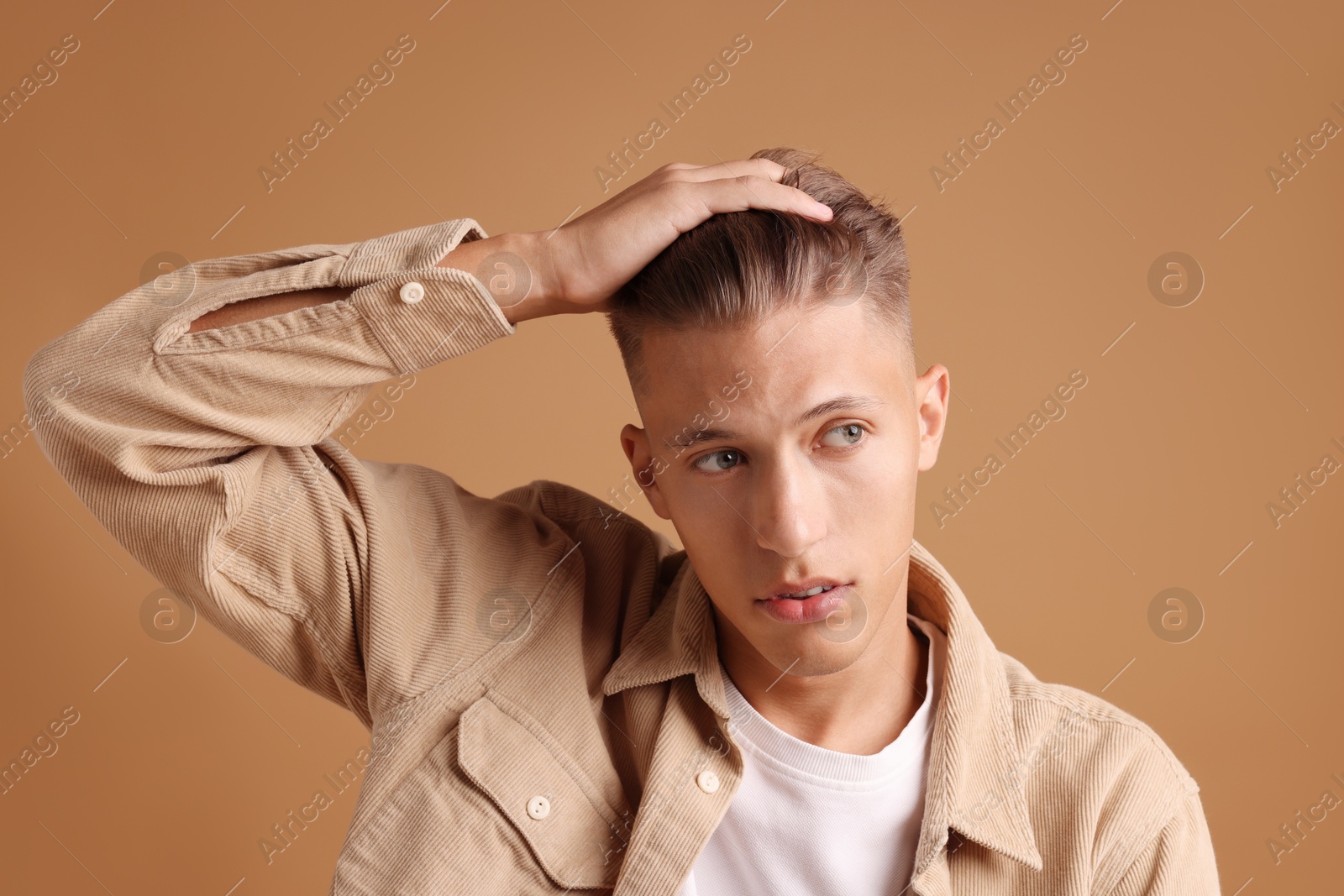 Photo of Confident young man with stylish haircut on brown background