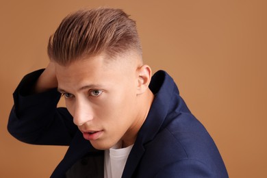 Photo of Confident young man with stylish haircut on brown background