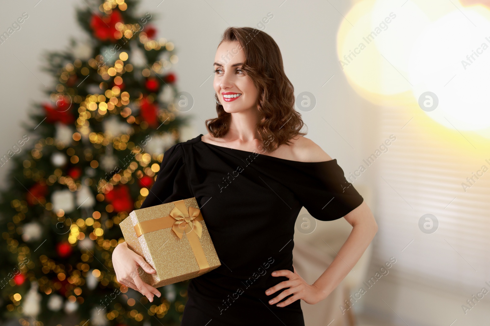 Photo of Smiling woman with perfect makeup and Christmas gift at home