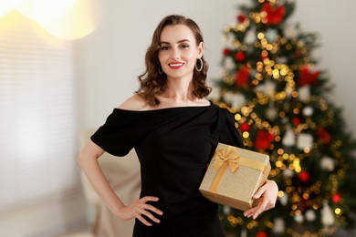 Photo of Smiling woman with perfect makeup and Christmas gift at home